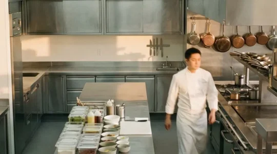 Vue aérienne d'une cuisine professionnelle en inox montrant les différentes zones de travail et les flux de circulation du personnel